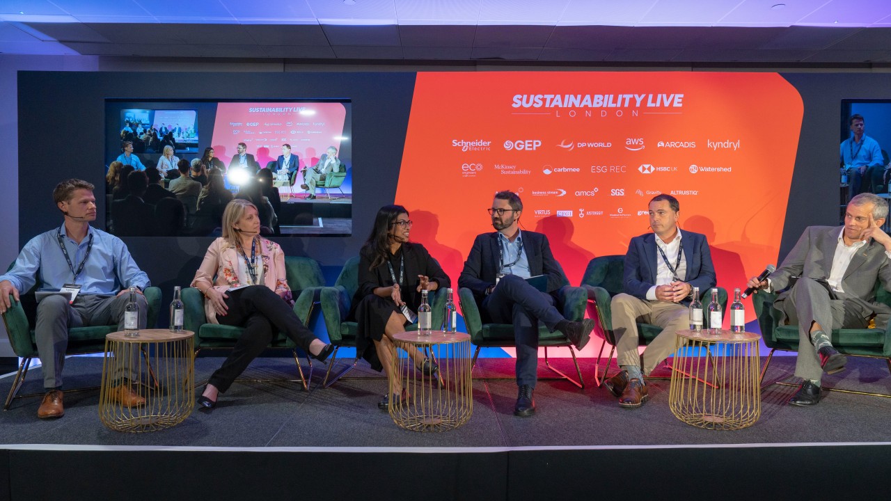 Panel at Sustainability Live London with six speakers and sponsor logos in the backdrop.