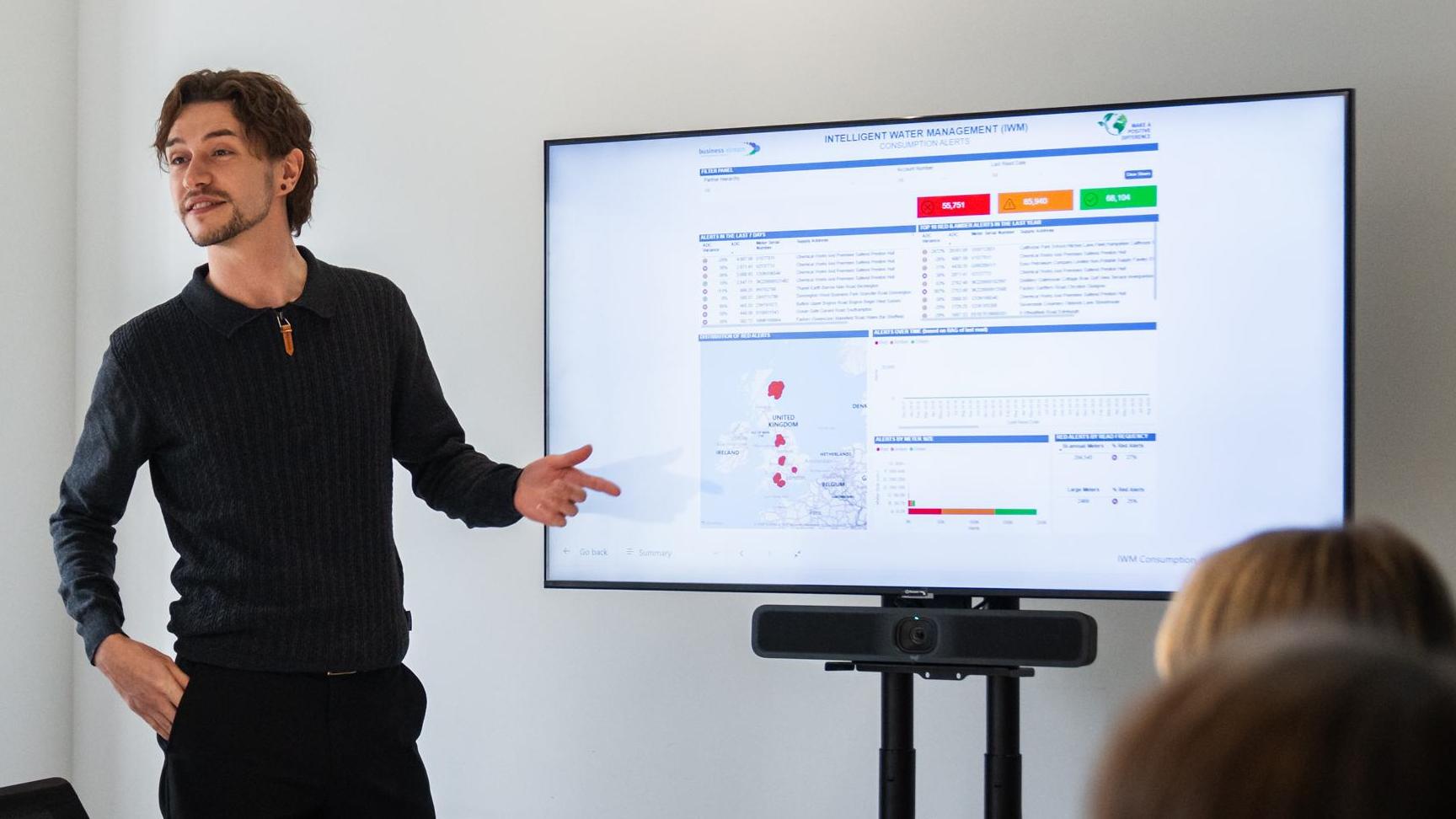 Man at large screen presenting data in a meeting room