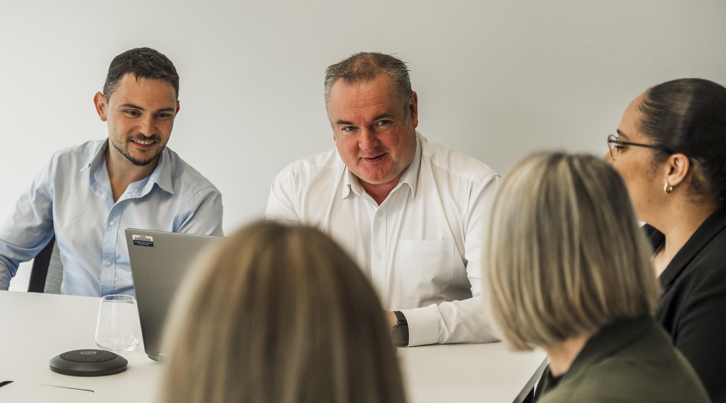 Close-up of two men and three women in a meeting scenario