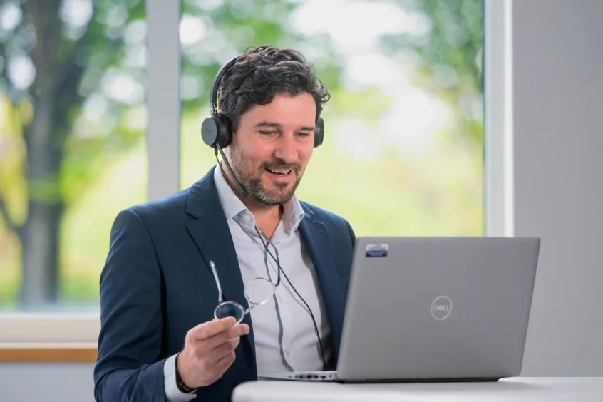 Man in suit with no tie on a video call using a laptop