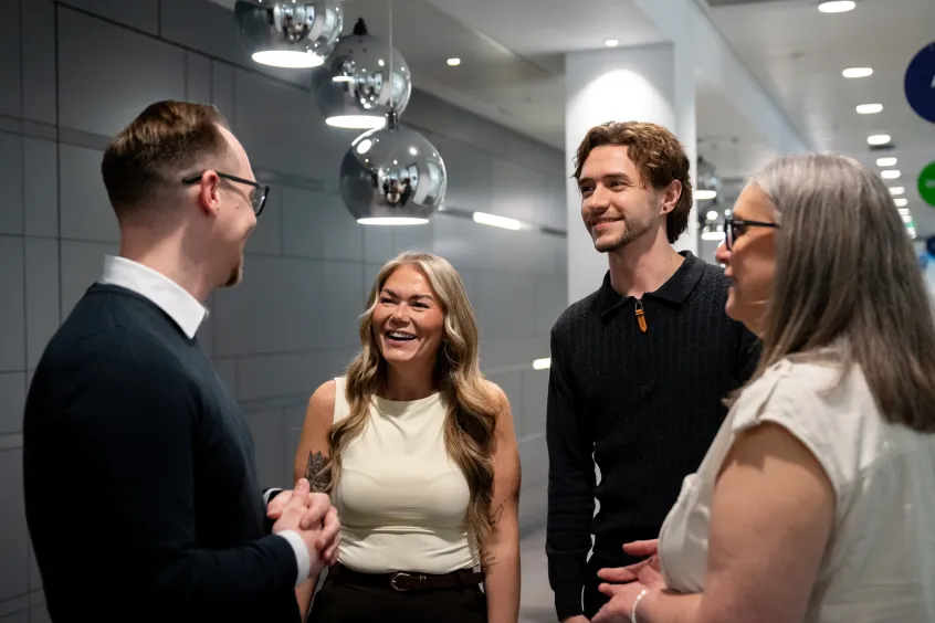 Two women and two men standing in a lobby talking and smiling.