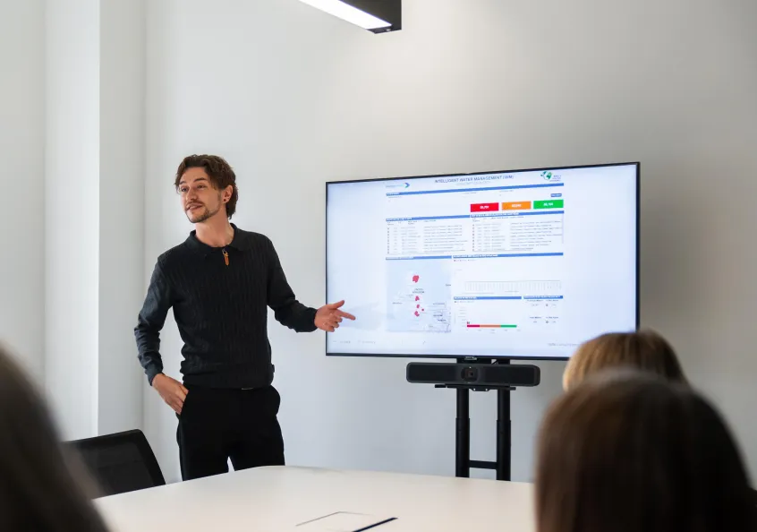Man at large screen presenting data in a meeting room