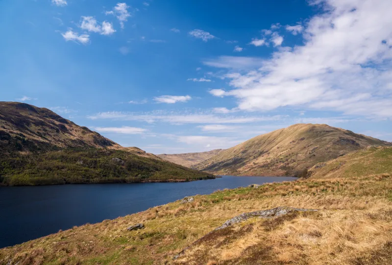 Glen Finglas reservoir with dry banks and a blue sky above