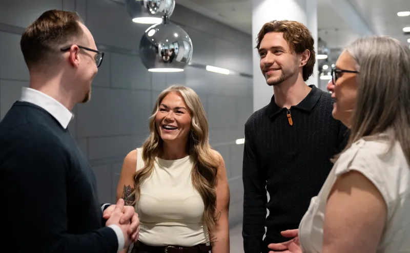 Four colleagues standing, chatting and smiling