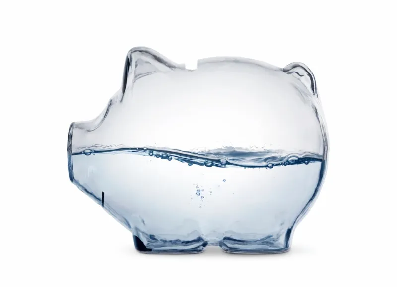 Transparent piggy bank half filled with water