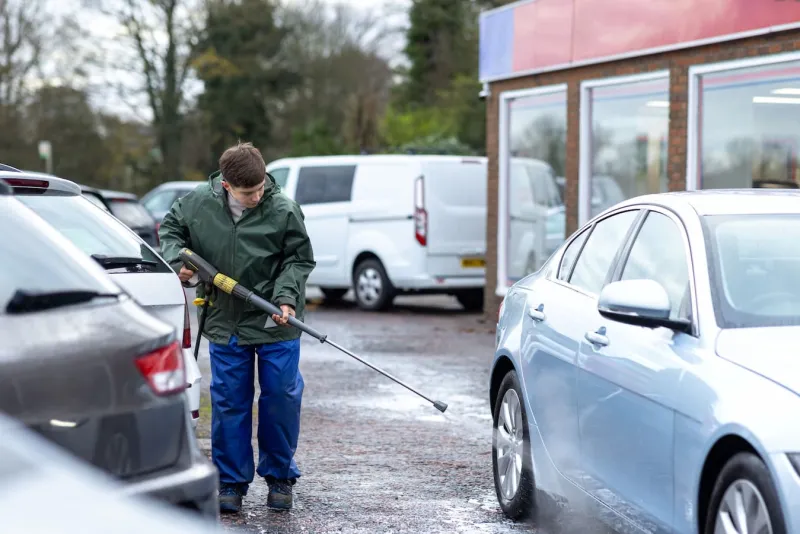 Young man washing car with pressure washer