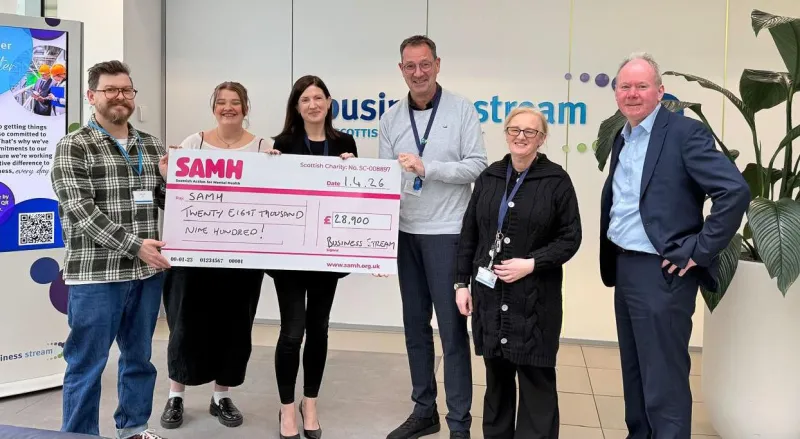 Six people in Business Stream reception area holding a large cheque for SAMH
